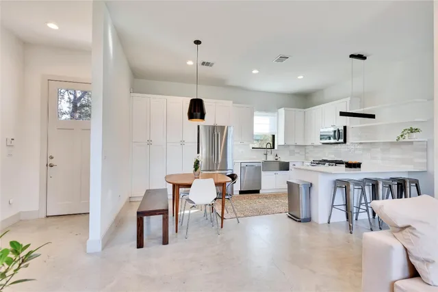 a large white kitchen with a table and chairs