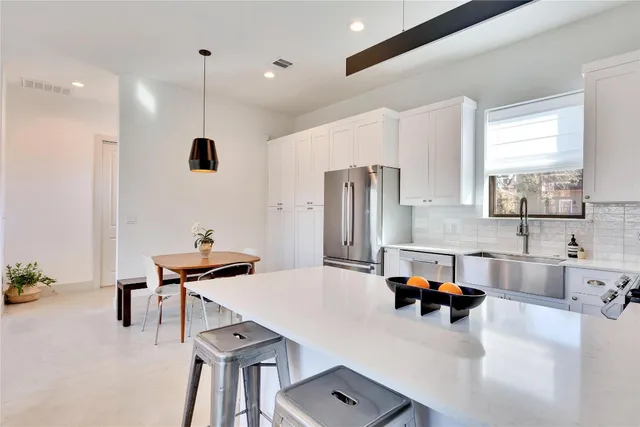 a kitchen with stainless steel appliances kitchen island granite countertop a refrigerator a sink and a stove