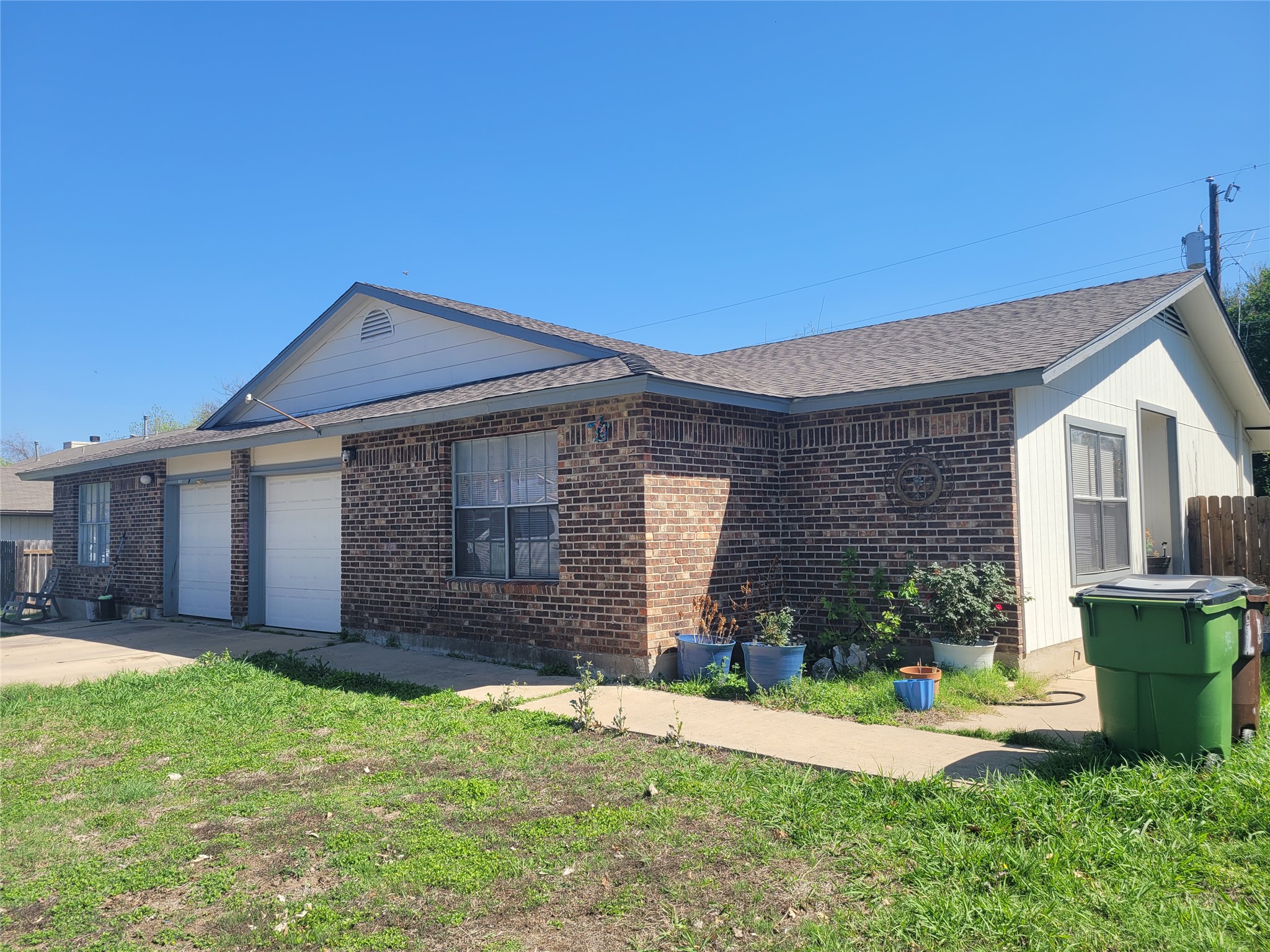 1011 Ridgemont Street Round Rock, TX 78664 - Photo 3 of 4 View of side of home with an attached garage, brick siding, roof with shingles, and concrete driveway
