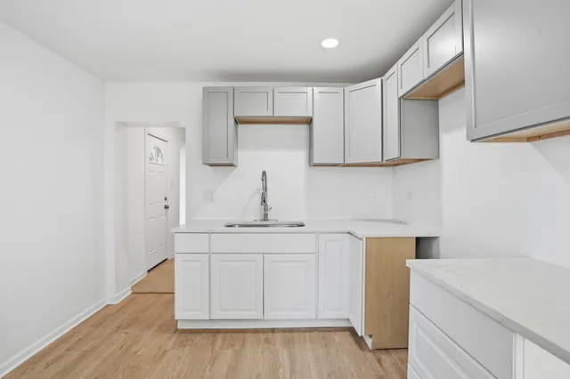 a kitchen with white cabinets and sink