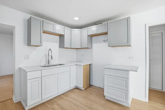 a kitchen with white cabinets and sink