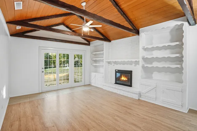 a view of a room with wooden floor a fireplace and windows