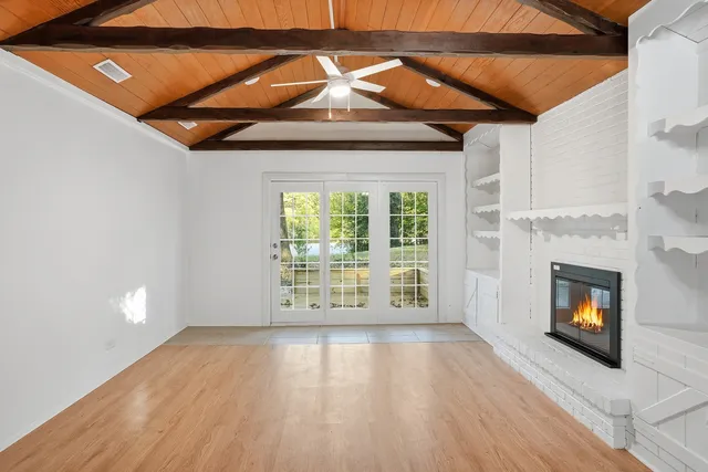 a view of an empty room with a fireplace and a window