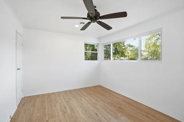 a view of empty room with wooden floor and fan