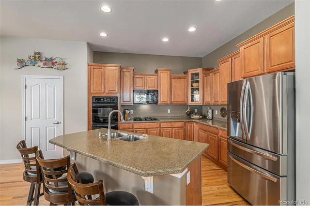 a kitchen with stainless steel appliances granite countertop a refrigerator a sink a stove and island