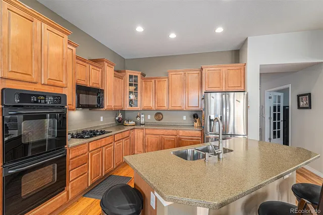 a kitchen with stainless steel appliances granite countertop a sink a stove and refrigerator