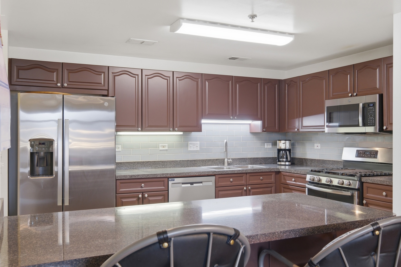 875 East 22nd Street, Unit 410 Lombard, IL 60148 - Photo 8 of 30 a kitchen with stainless steel appliances granite countertop a stove a sink dishwasher a refrigerator with a dining table and chairs