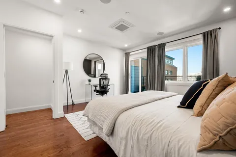 a bedroom with a bed a mirror and a large window