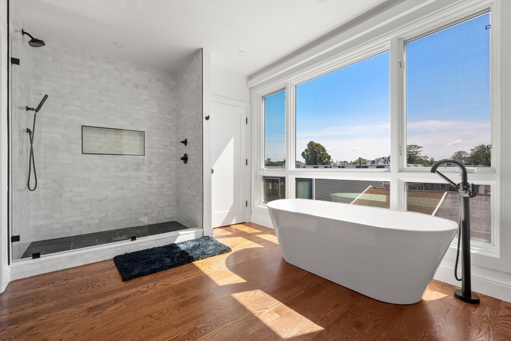 7 A Kemble Place Boston, MA 02127 - Photo 13 of 26 a living room with furniture a large window and wooden floor