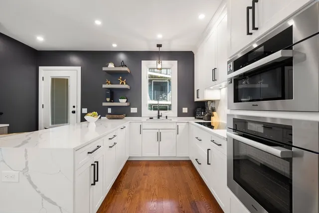 a large white kitchen with stainless steel appliances granite countertop a stove and a sink