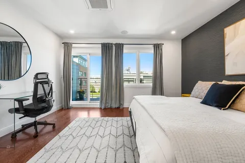 a bedroom with a bed a mirror and a window with wooden floor
