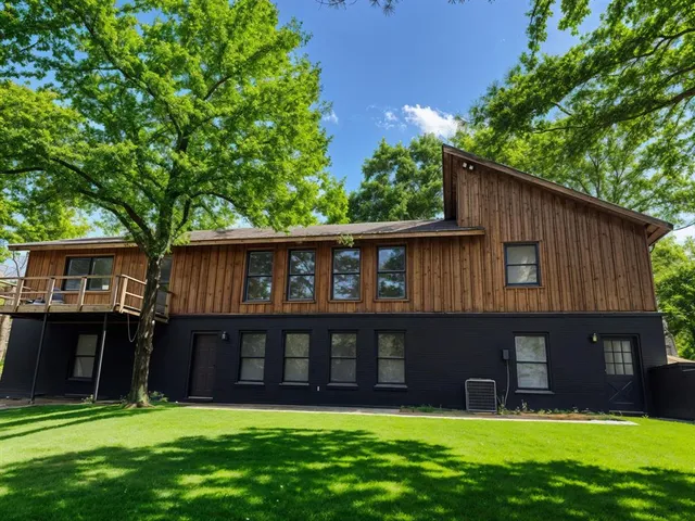 a view of a house with a yard and a large tree