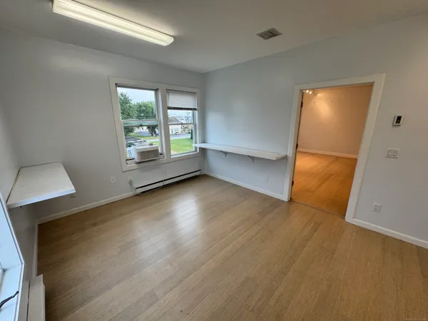 an empty room with wooden floor and windows