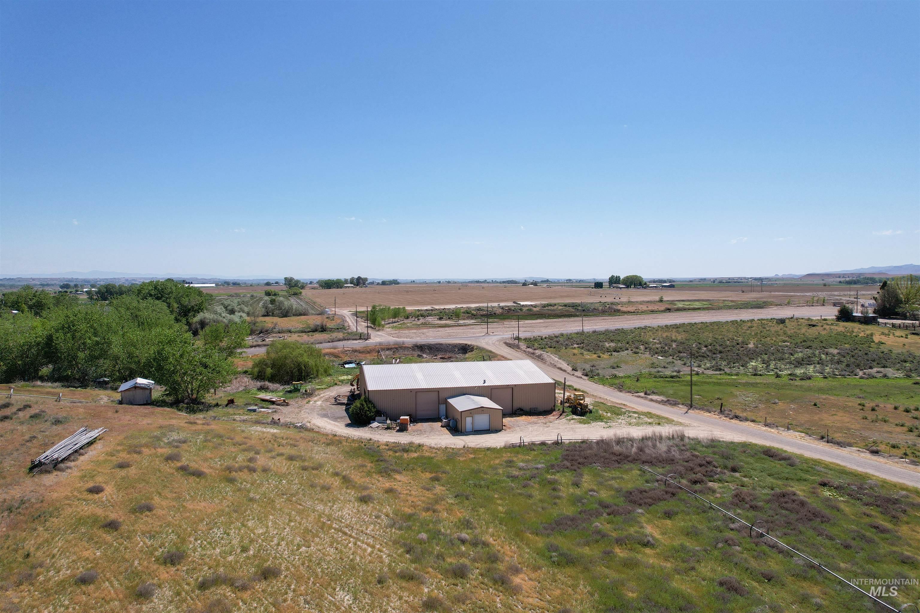 1030 Desert Glen Road Adrian, OR 97901 - Photo 45 of 47 Expansive land parcel featuring a large light-colored building with a silver roof, a smaller detached building, and a wide gravel driveway