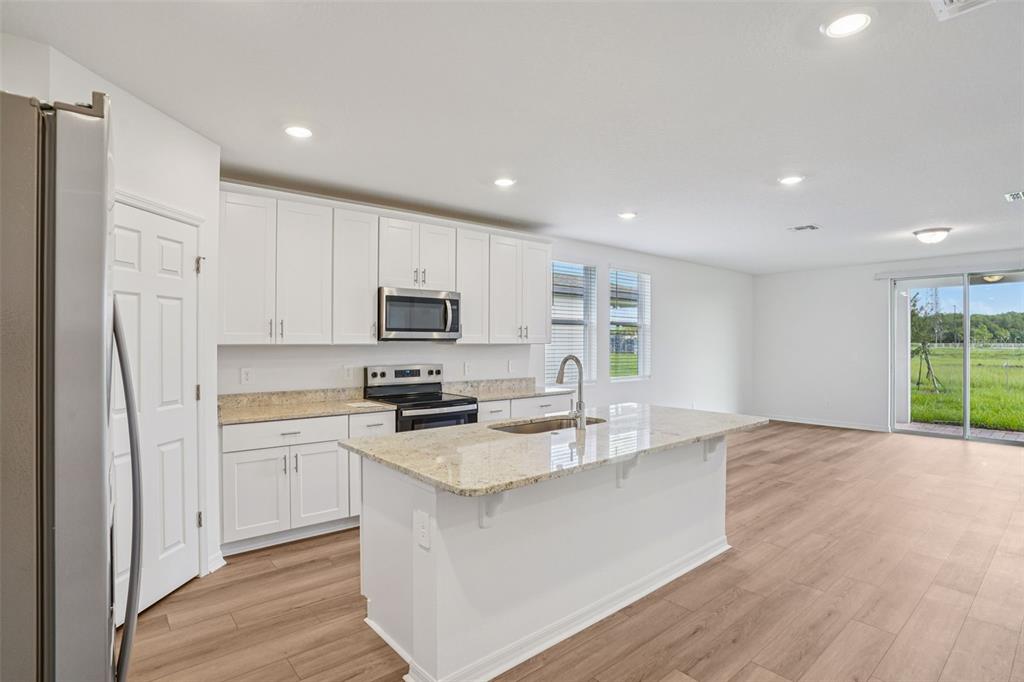 4519 Windy Oak Way St. Cloud, FL 34772 - Photo 11 of 40 a kitchen with stainless steel appliances granite countertop a refrigerator a stove top oven a sink and dishwasher with wooden floor