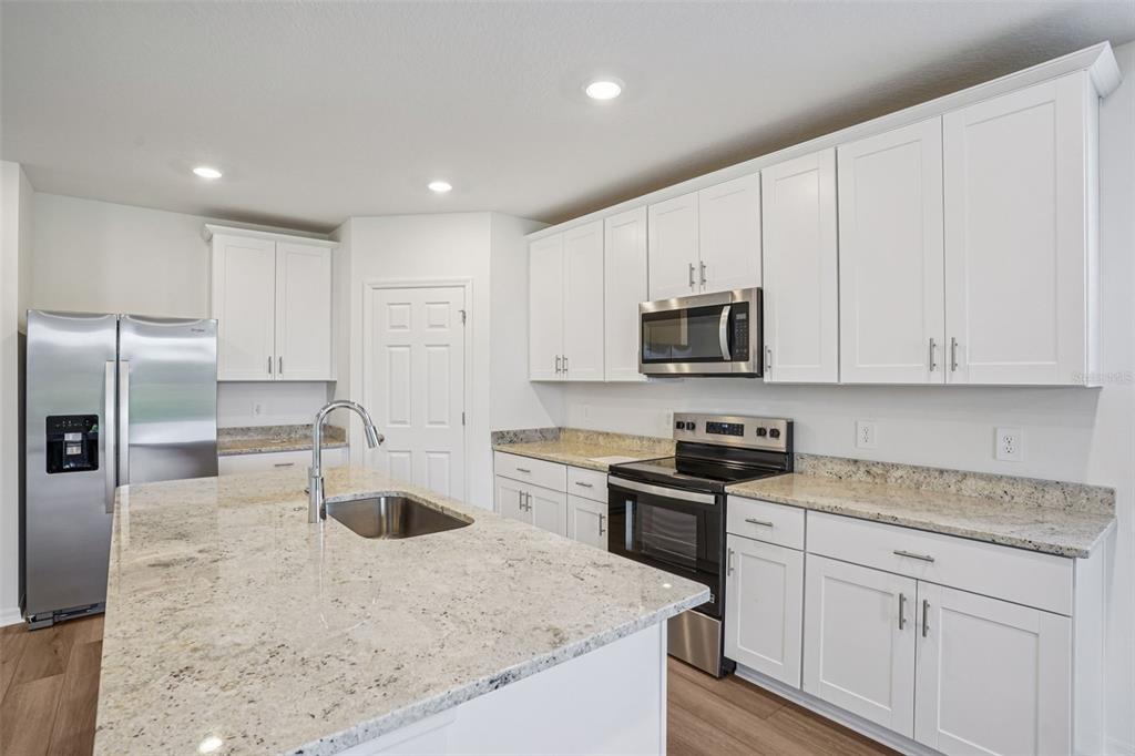 4519 Windy Oak Way St. Cloud, FL 34772 - Photo 13 of 40 a kitchen with kitchen island granite countertop a sink a stove and refrigerator