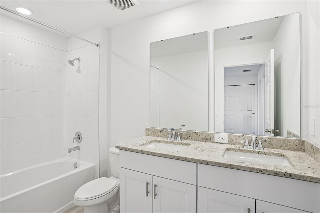 4519 Windy Oak Way St. Cloud, FL 34772 - Photo 31 of 40 a bathroom with a granite countertop sink a toilet and shower