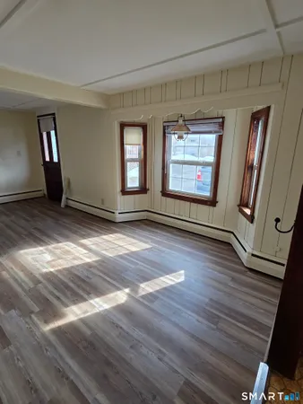 a view of an empty room with wooden floor and a window