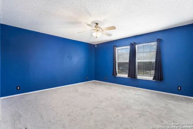 a view of an empty room with chandelier fan and windows