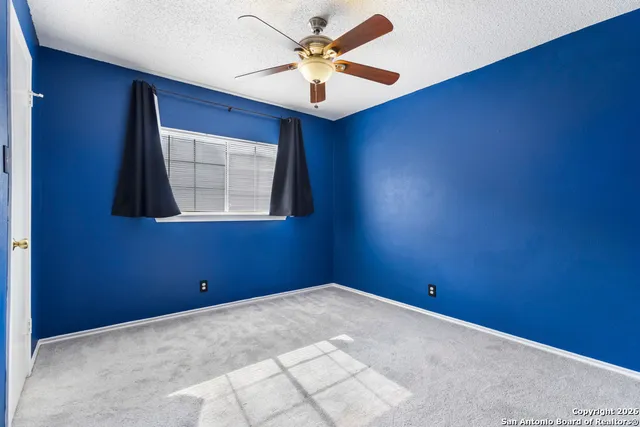 an empty room with a window and a fan
