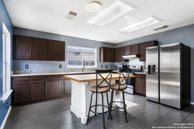 a kitchen with stainless steel appliances granite countertop a table chairs microwave and sink