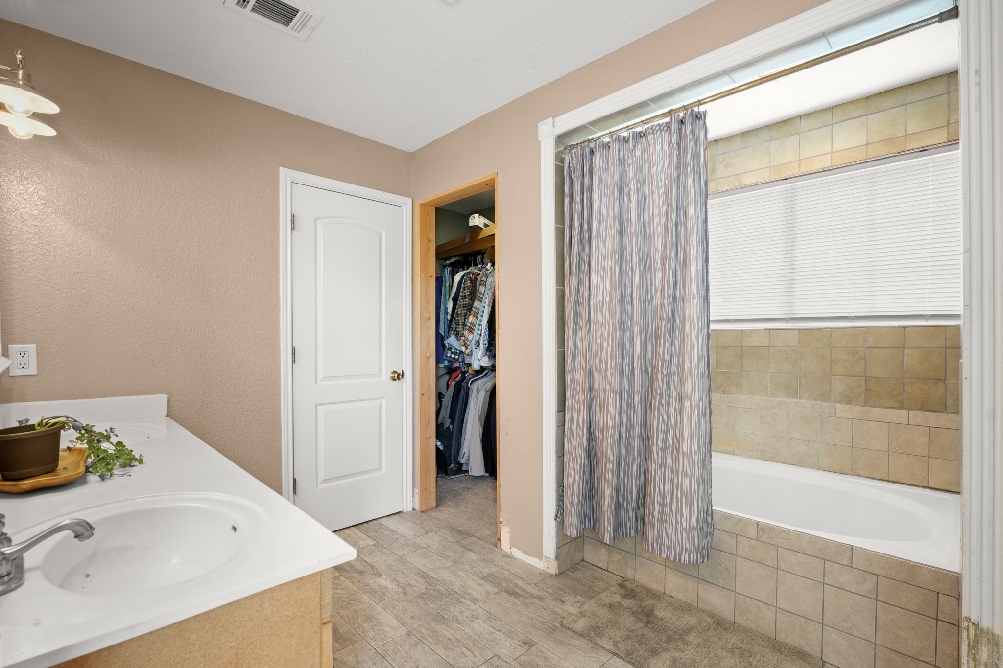 9725 Bock Road Buda, TX 78610 - Photo 22 of 32 A well-appointed bathroom features a single vanity, a tiled tub, and a convenient walk-in closet.