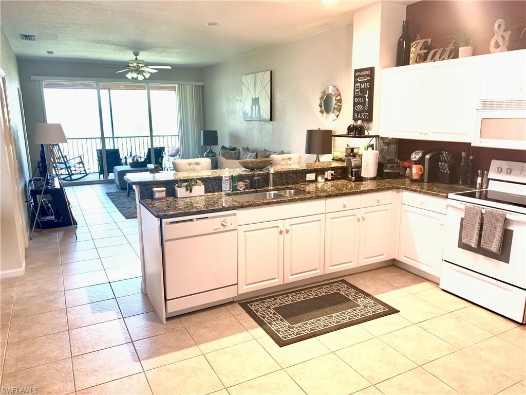 10045 Heather Lane, Unit 2203 Naples, FL 34119 - Photo 3 of 23 a large white kitchen with a stove a sink a washer dryer and a dining table