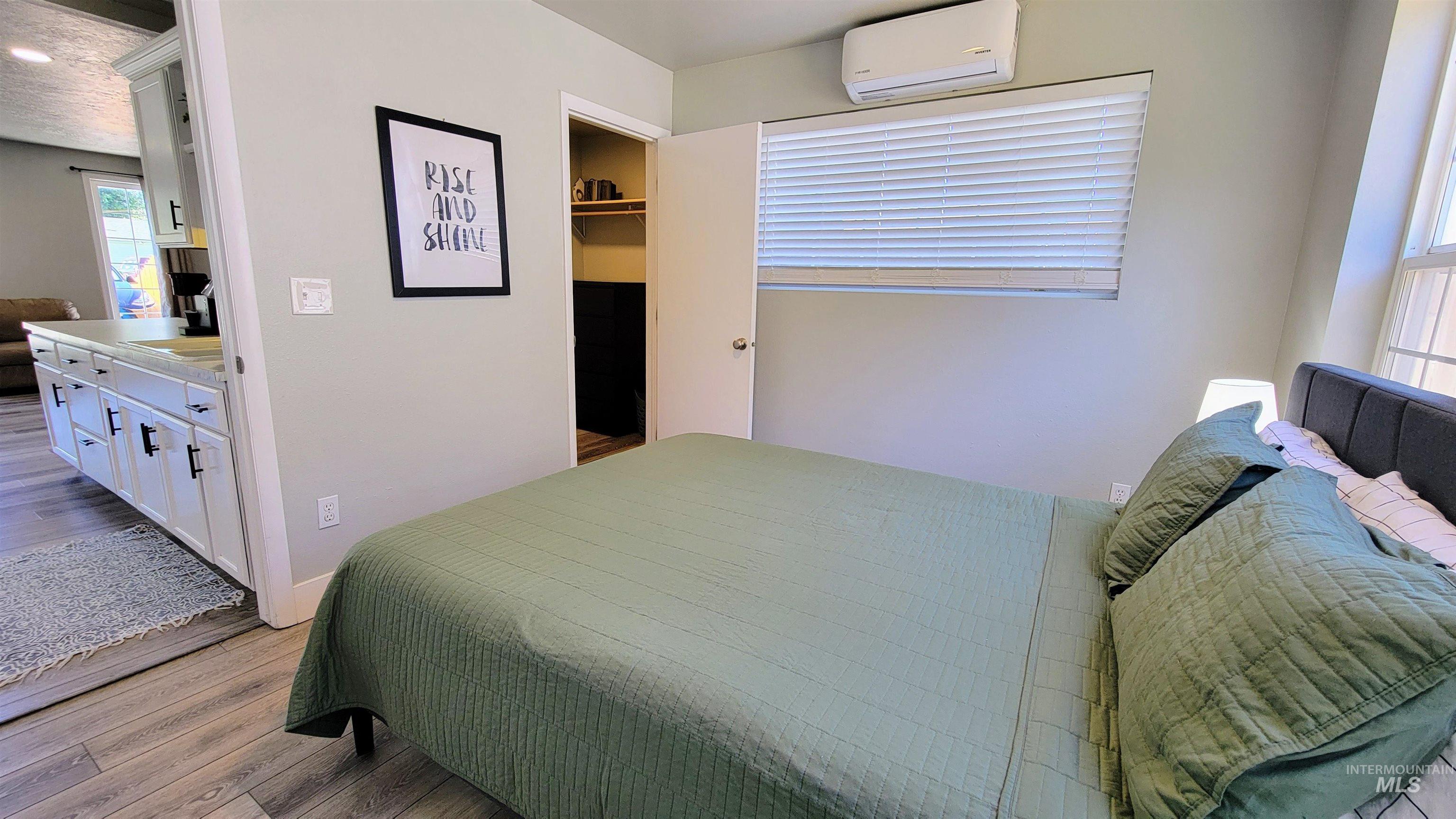 814 Baker Street Boise, ID 83706 - Photo 22 of 26 Bedroom featuring wood-finish flooring, a mini-split AC unit, a window with horizontal blinds, and an open closet