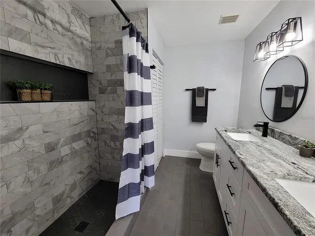 a spacious bathroom with a granite countertop toilet a sink and a mirror