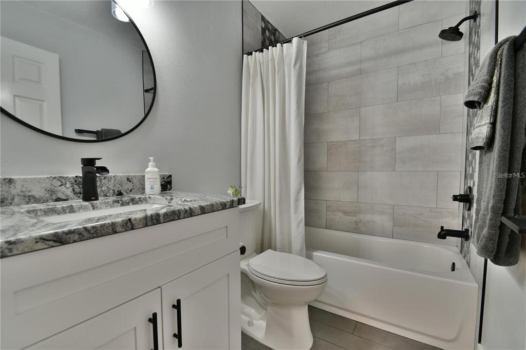 1801 East Lake Road South, Unit 15E Palm Harbor, FL 34685 - Photo 16 of 24 a bathroom with a granite countertop sink toilet and shower