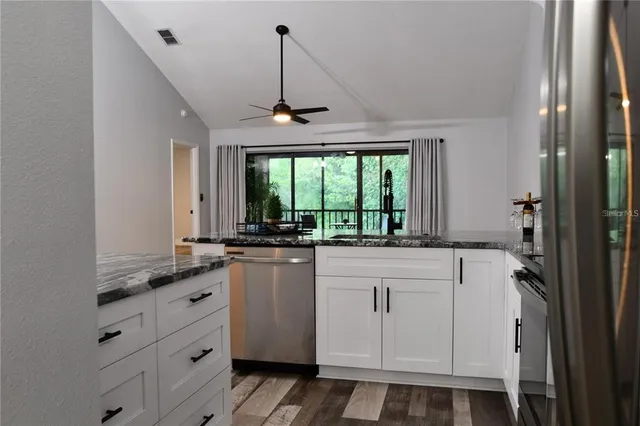 a kitchen with granite countertop white cabinets and white appliances