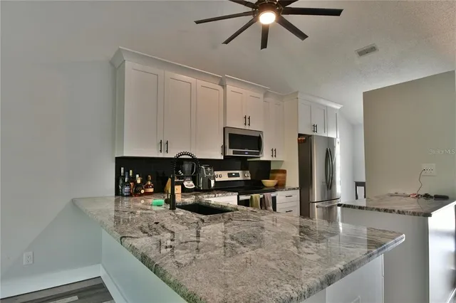 a kitchen with granite countertop a sink a counter top space appliances and cabinets