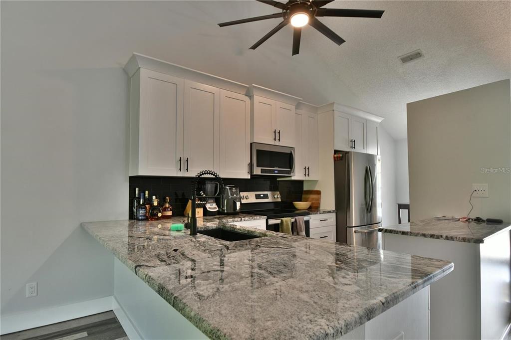 1801 East Lake Road South, Unit 15E Palm Harbor, FL 34685 - Photo 6 of 24 a kitchen with granite countertop a sink a counter top space appliances and cabinets