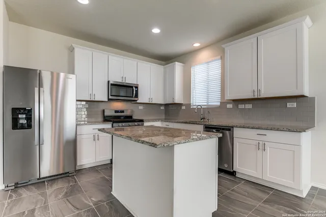 a kitchen with stainless steel appliances granite countertop a stove a sink and a refrigerator