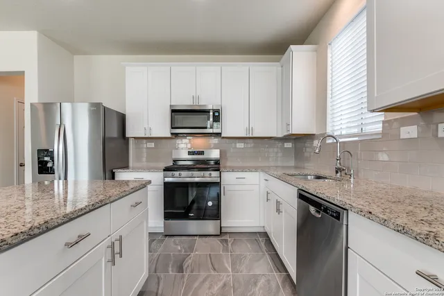 a kitchen with stainless steel appliances granite countertop a sink stove microwave and refrigerator