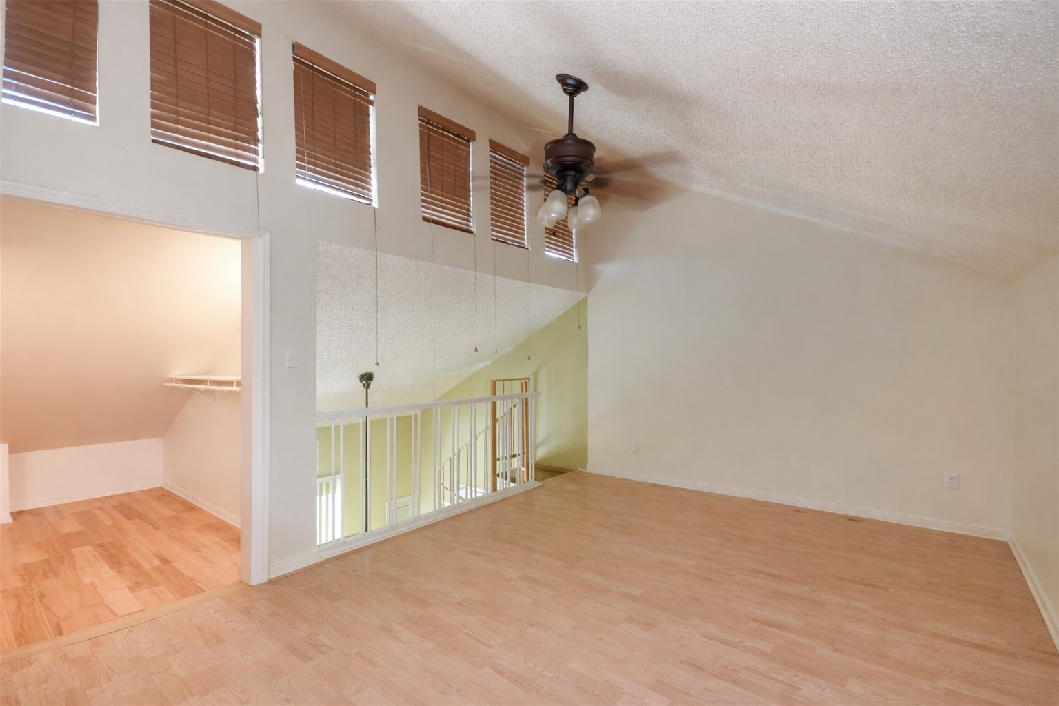 3115 Tom Green Street, Unit 404 Austin, TX 78705 - Photo 19 of 19 Upper-level room featuring wood-finish flooring, a vaulted ceiling, and a ceiling fan with integrated lighting