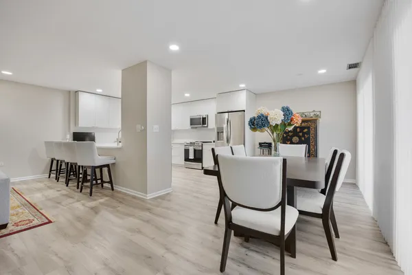 a kitchen with a dining table chairs and refrigerator