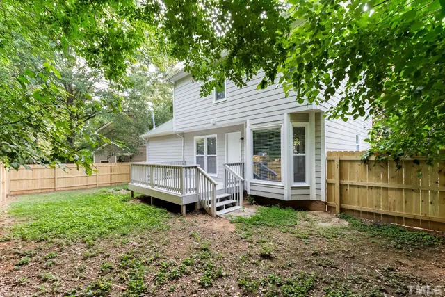 a view of a house with a yard chairs and a large tree