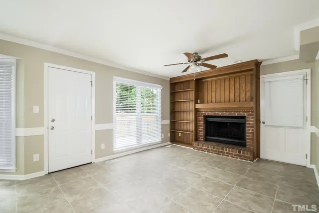 an empty room with a fireplace and a ceiling fan