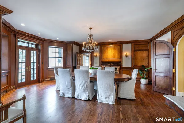 a dining room with wooden floor a chandelier a glass table and chairs