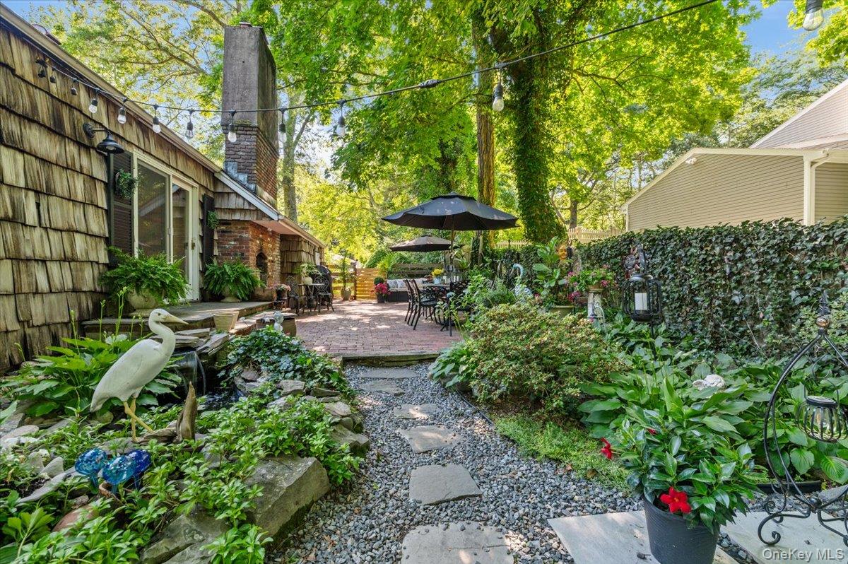 10 Rancher Place Huntington, NY 11743 - Photo 38 of 44 Spacious outdoor patio area featuring a brick paver surface, mature trees, and string lighting