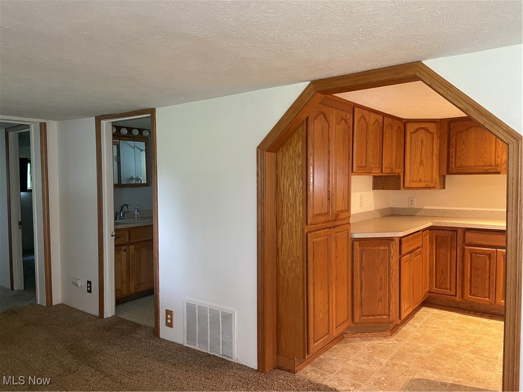 14092 Hatfield Road Rittman, OH 44270 - Photo 9 of 38 Kitchen with brown cabinetry, light countertops, and a textured ceiling