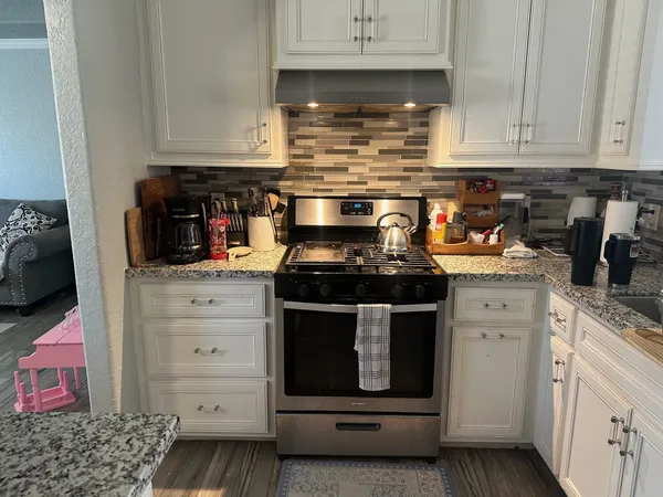 a kitchen with stainless steel appliances granite countertop a stove and cabinets