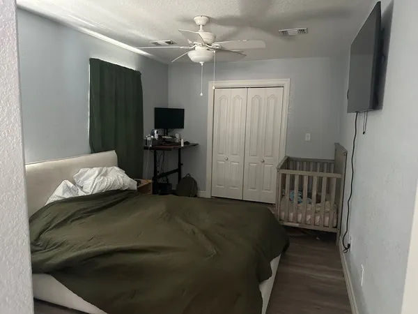a bedroom with a bed and a flat tv screen on dresser