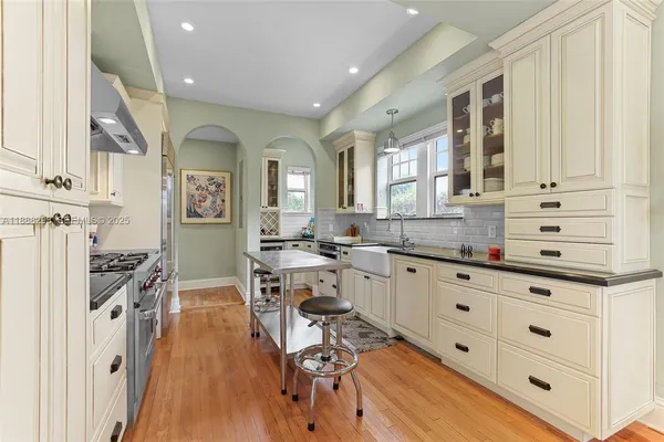 a open kitchen with granite countertop a stove a sink a dining table and chairs with wooden floor