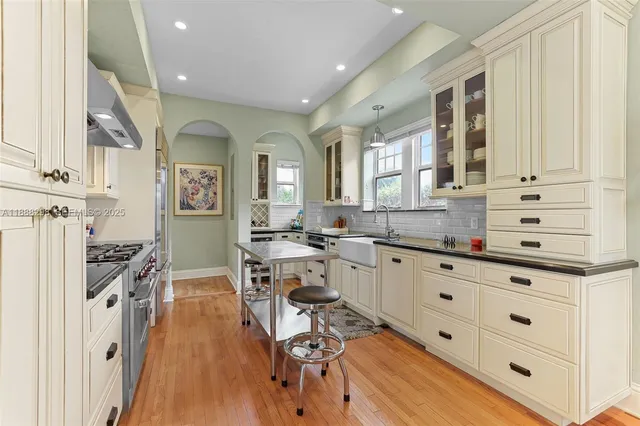 a open kitchen with granite countertop a stove a sink a dining table and chairs with wooden floor