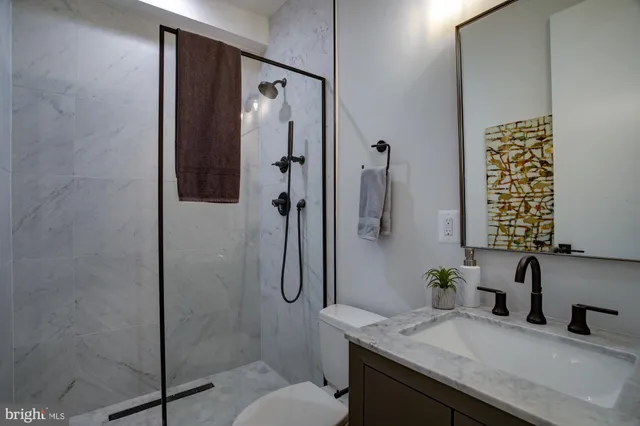 a bathroom with a granite countertop sink a toilet and shower
