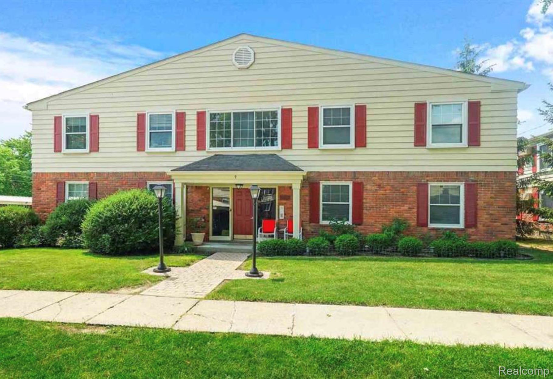 Two-story property featuring brick and siding with red window shutters