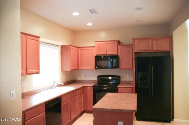 a kitchen with kitchen island granite countertop a refrigerator stove top oven and sink