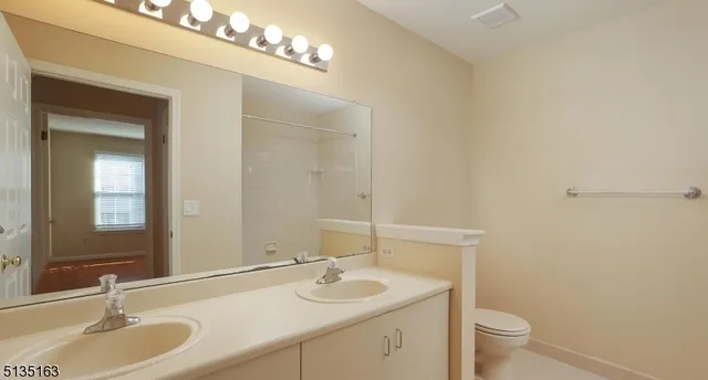 a bathroom with a granite countertop sink a toilet and a mirror